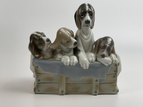 Lladro figur med hunde, formentlig af Juan Huerta, 4 hvalpe med tæppe over sig sidder på en "trækasse", 20. århundrede