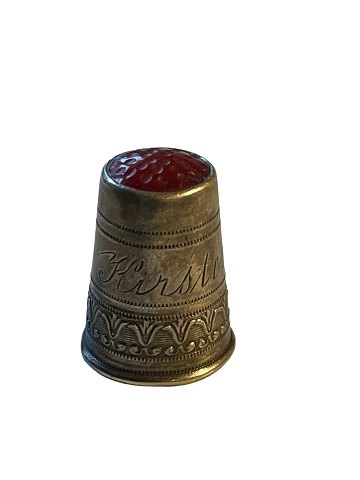Fingerbøl af sølv med rødt glas i toppen. Stemplet 830 samt mestermærke. Indgraveret "Kirsten".